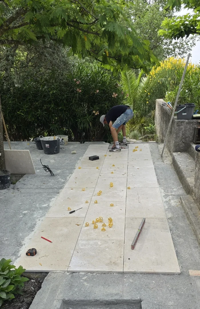 Pose de dallage grand format sur une terrasse extérieure par Atlas Construction, dans un jardin méditerranéen