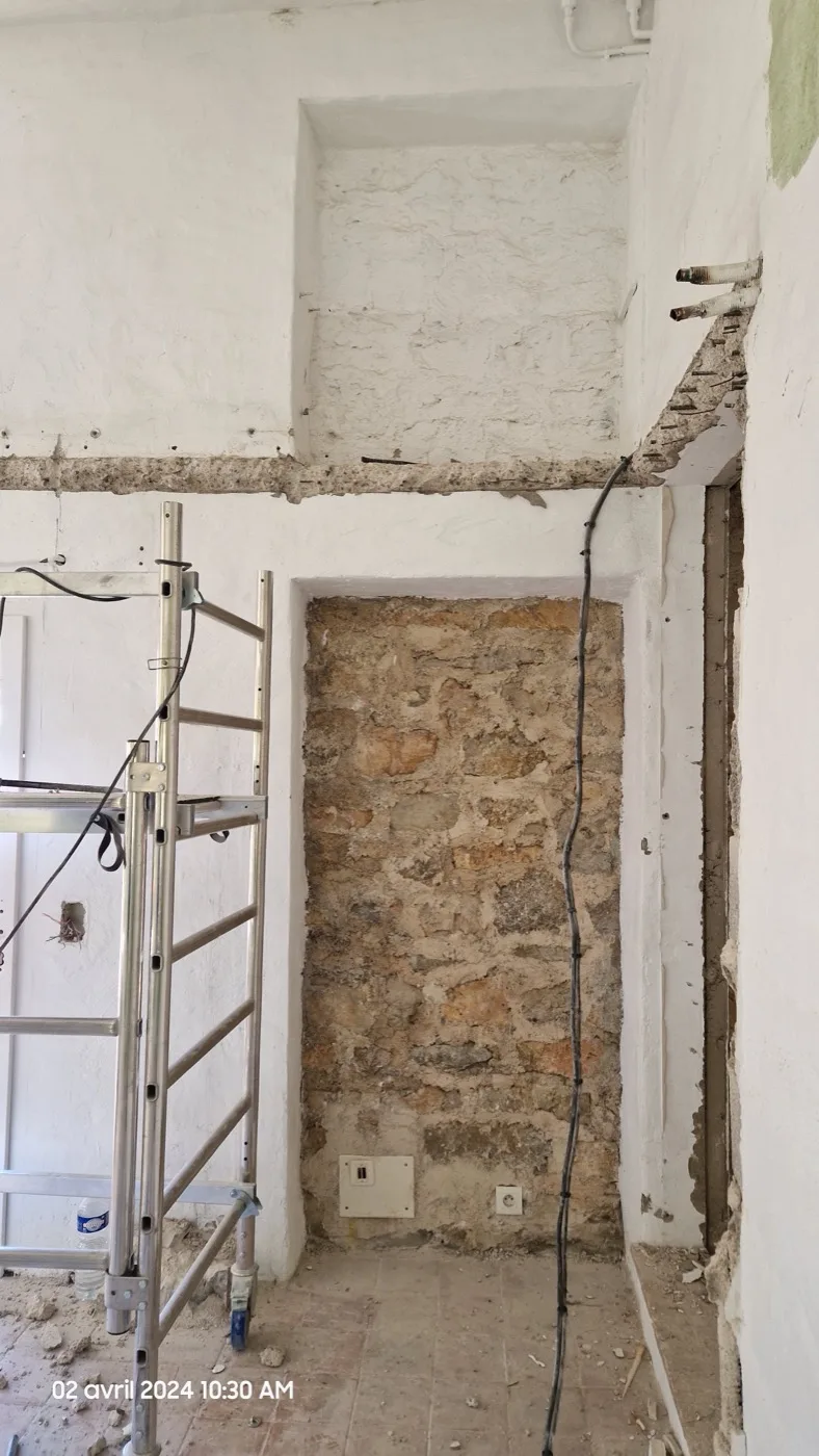 Mur en pierre apparente et enduits en cours de finition lors d'une rénovation Atlas Construction